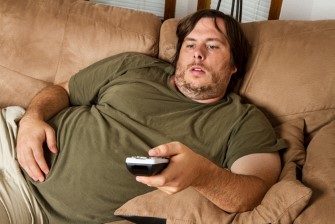 Overweight,Guy,Sitting,On,The,Couch,With,Remote,In,Hand